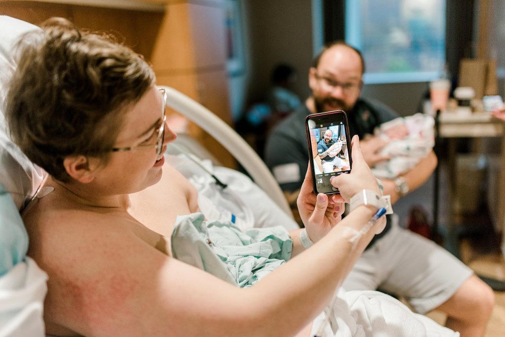 Mom taking photo of daddy and new baby after birth in Baylor Hospital