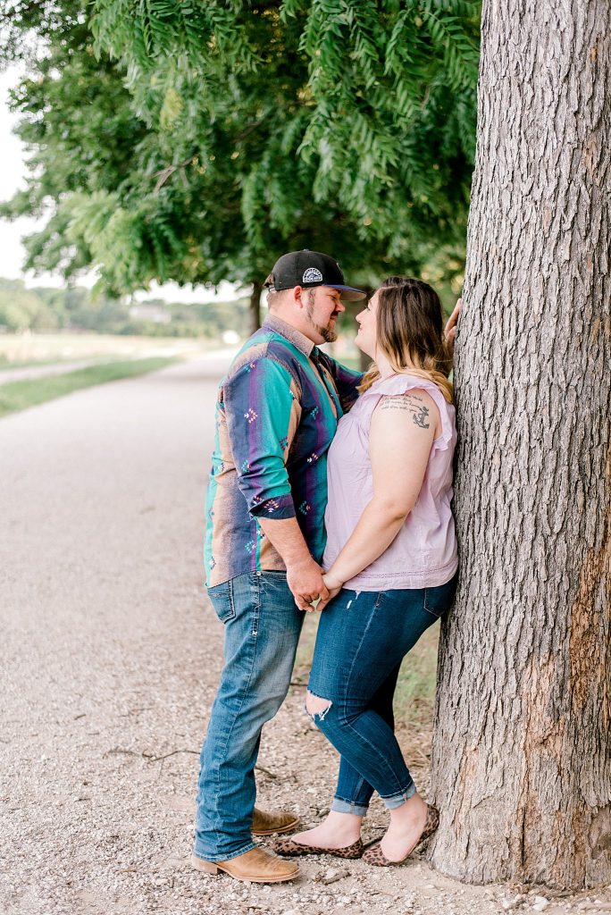 Fort Worth Engagement Session with couple leaning on tree beside the river