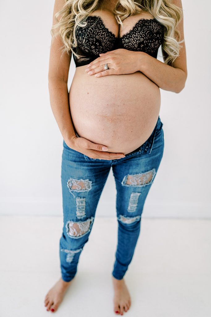 Pregnant woman holding belly in ripped up jeans