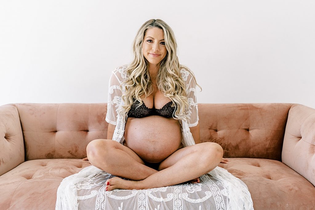 Pregnant woman sitting in lingerie on couch in Fort Worth maternity session