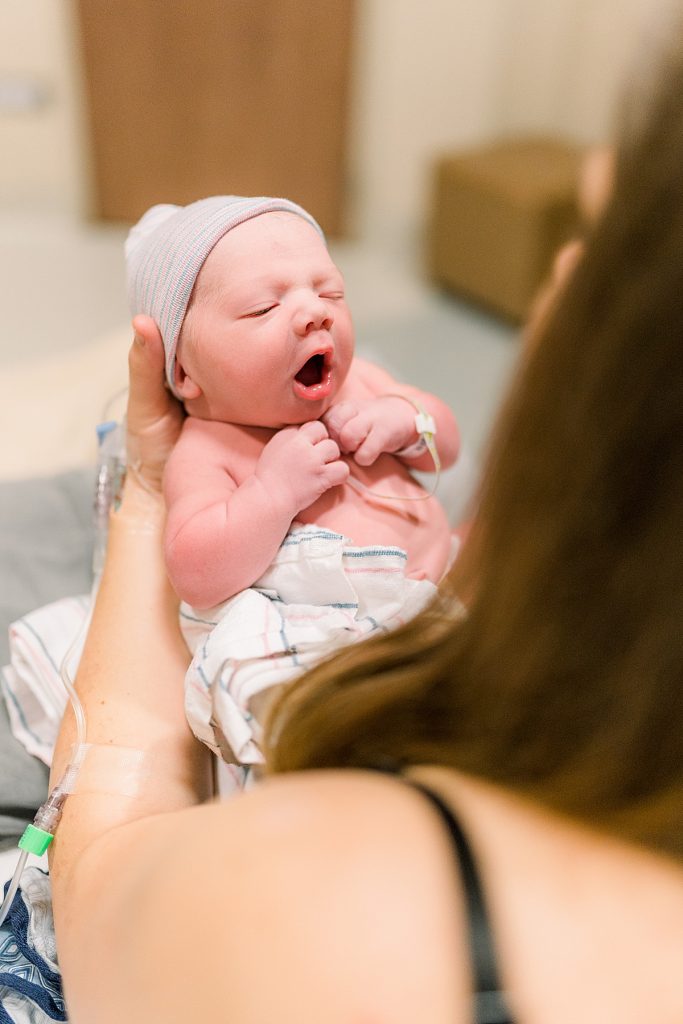 Newborn baby yawning while in mother's hands