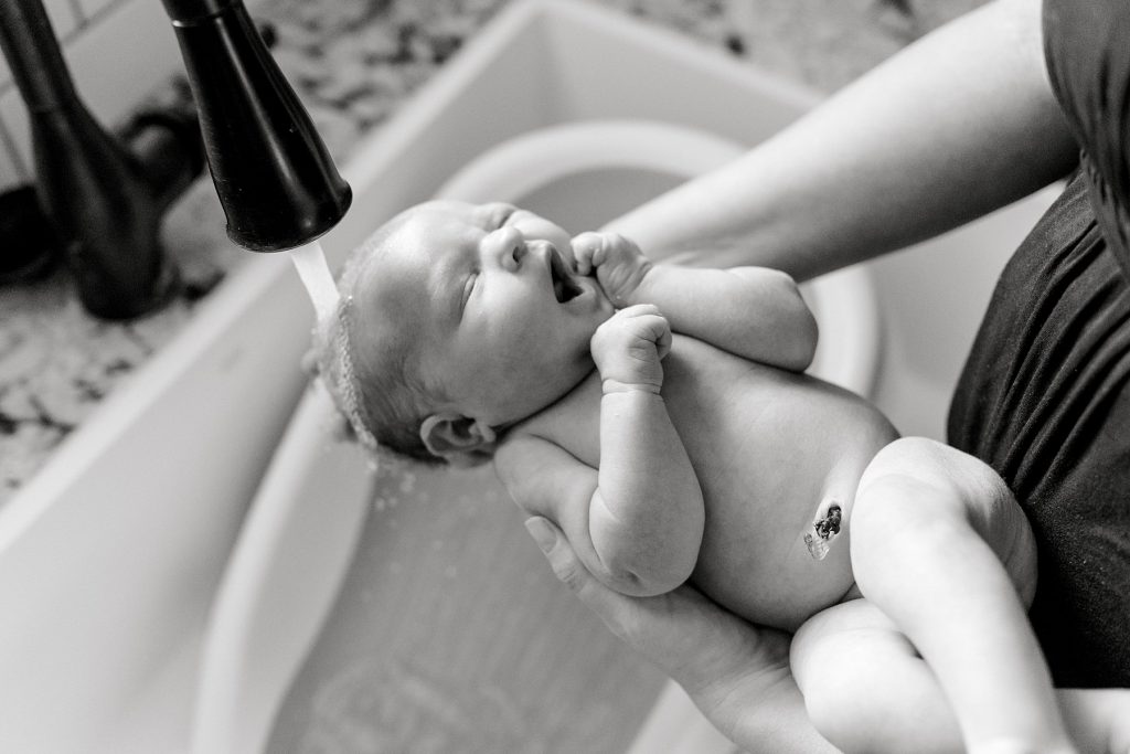 BW baby yawning while facet runs water over head during her lifestyle newborn session 