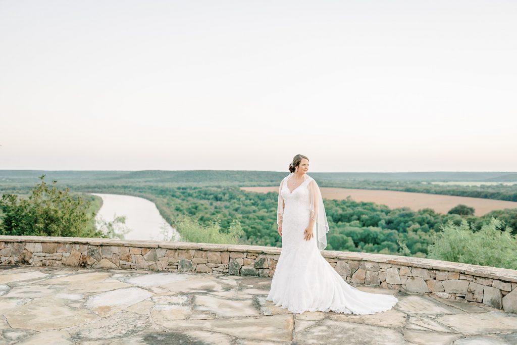 Bride standing on balcony in front of river at Wildcatter Ranch Texas bridal session