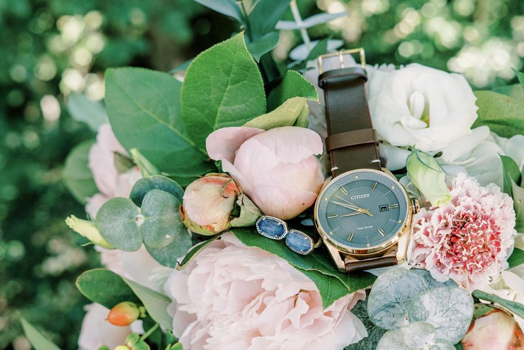 Watch and earrings laying in bridal bouquet