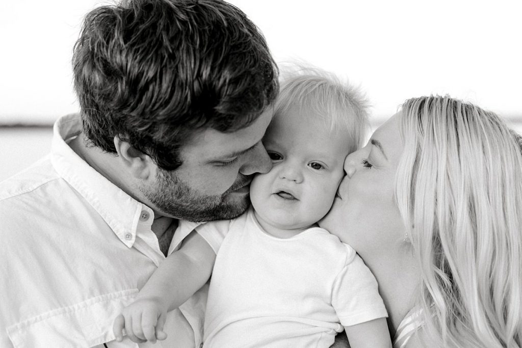 BW Parents kissing toddler on either side of face