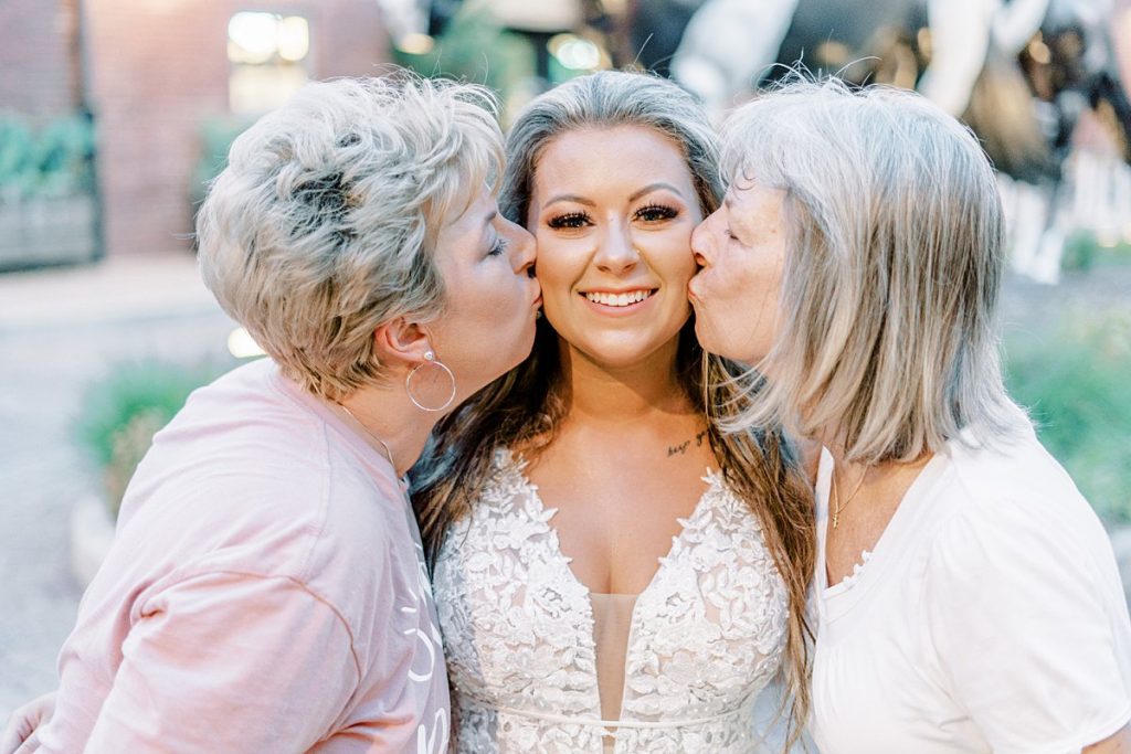 Bride being kissed on cheeks by mother and grandmother