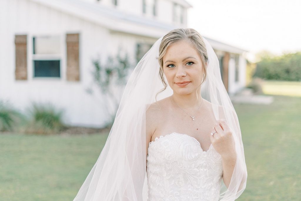 Bride holding touching wedding veil in Five Oaks Farms Bridal Sessio