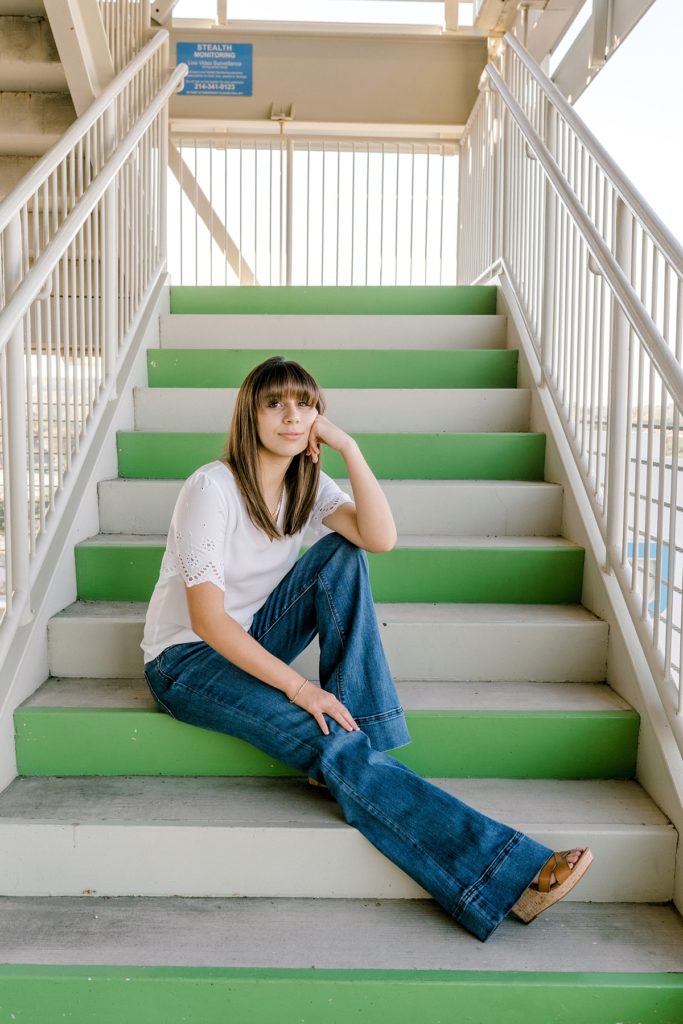 Girl sitting on green stairs in Texas senior session