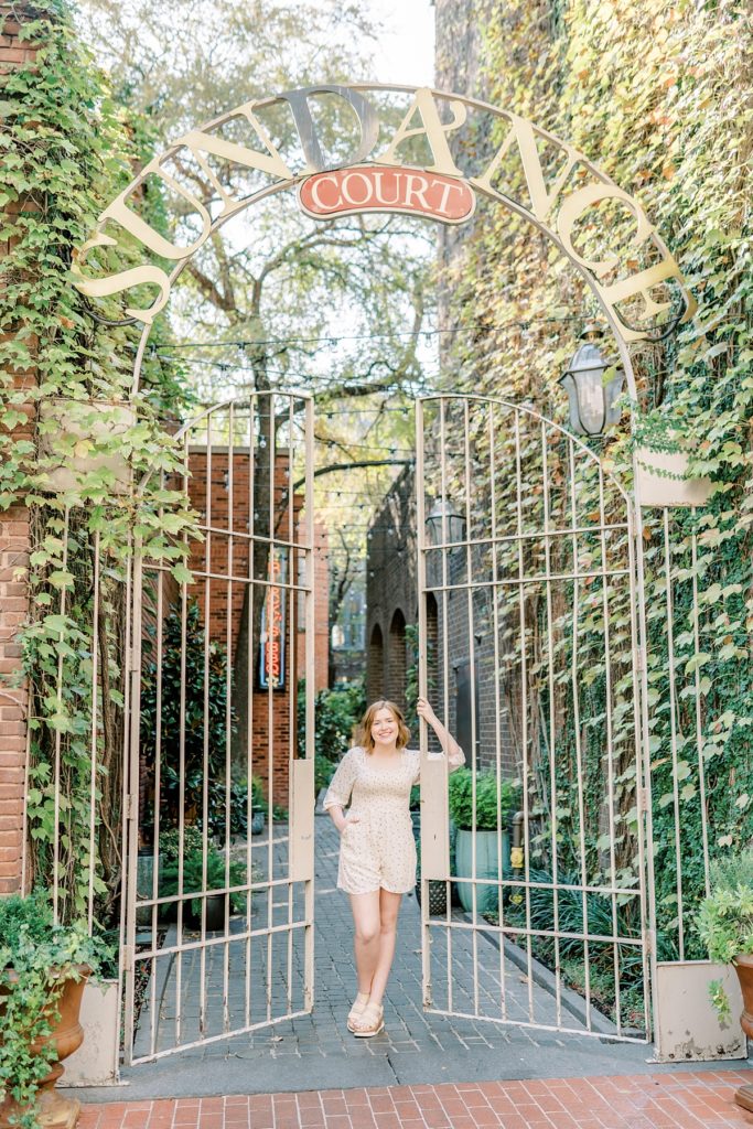 girl standing next to gate at Sundance Court for 2021 high school senior session