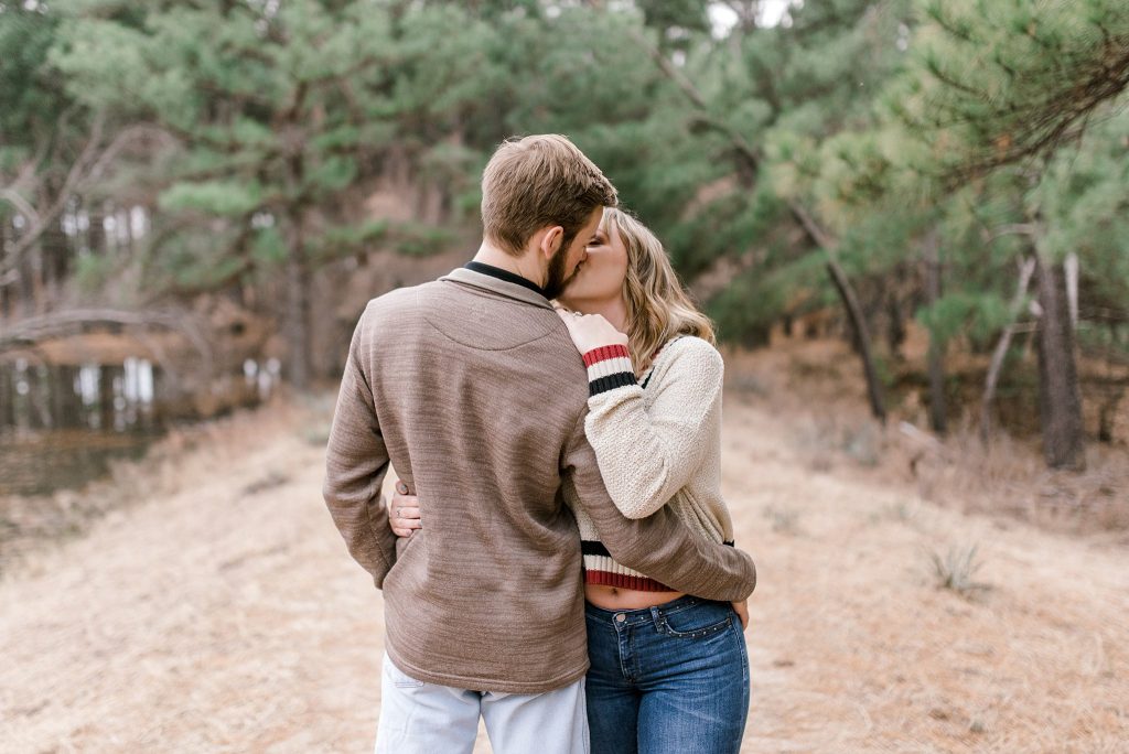 engagement photo with bride and groom kissing in pine trees