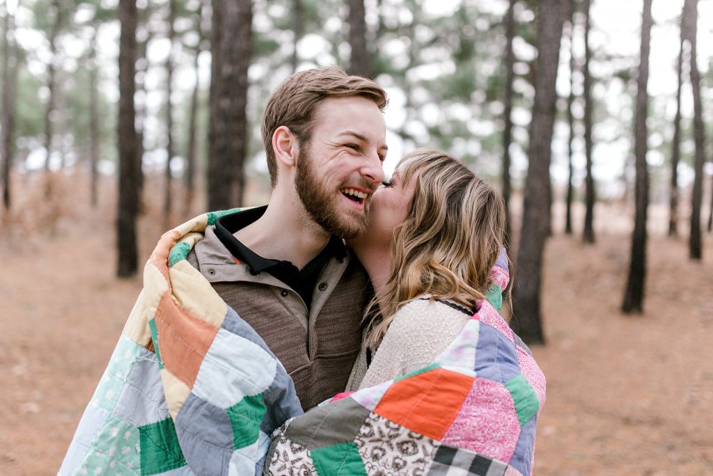 engagement photo with bride and groom laughing in pine trees