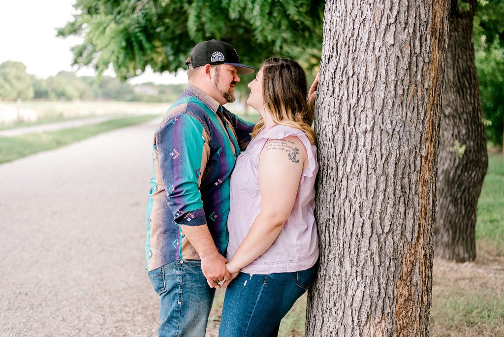Fort Worth Engagement Session with couple leaning on tree beside the river