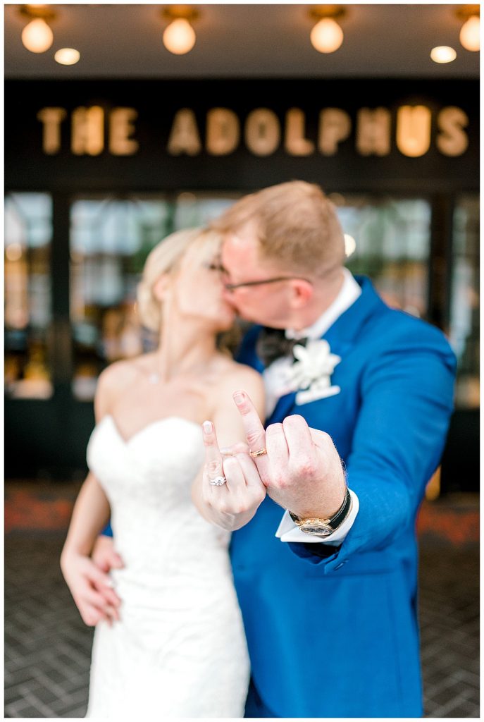 Bride and groom kissing and holding up their ring fingers to the camera| Dallas Texas Adolphus wedding