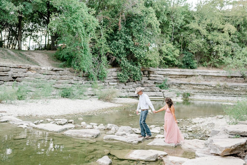Walking across walks at the waterfall during their engagement session