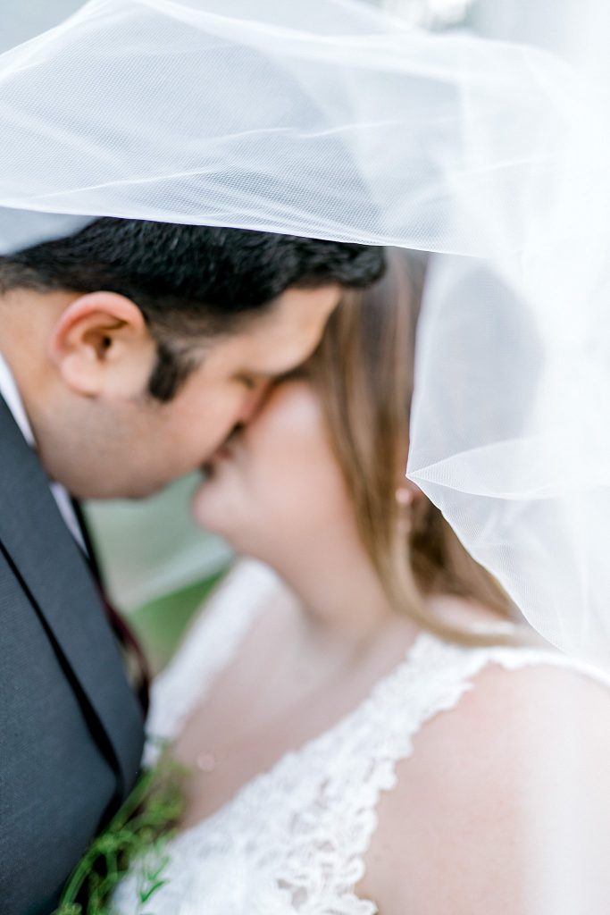 Bride and Groom under brides veil while kissing during their Mansfield anniversary session 