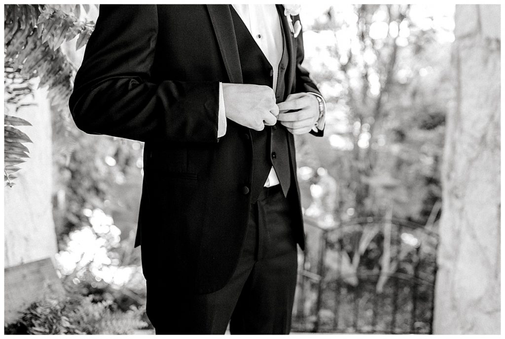 Black and white of groom buttoning suit