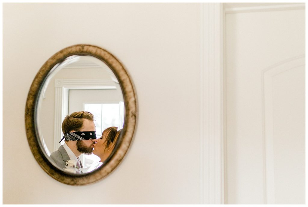 Blindfolded groom and bride kiss shot in oval mirror| first look