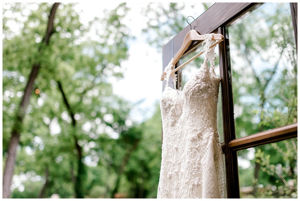 Wedding gown hanging on glass door outside