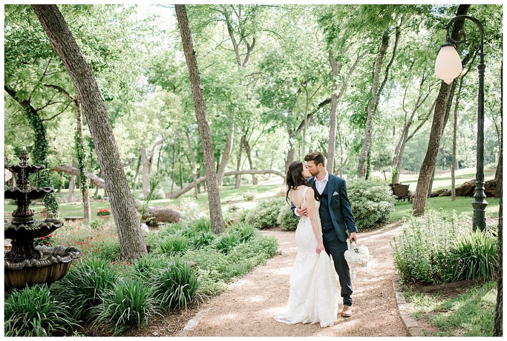 Bride and groom kissing on tree lined path