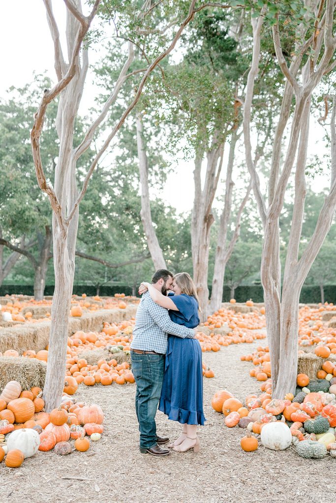 Couple cuddling among the pumpkins during their engagement session