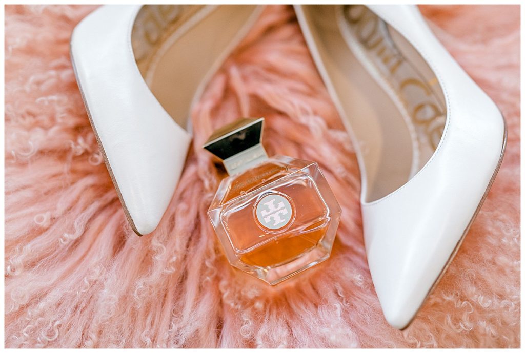 Wedding shoes and perfume bottle on pink fuzzy fabric