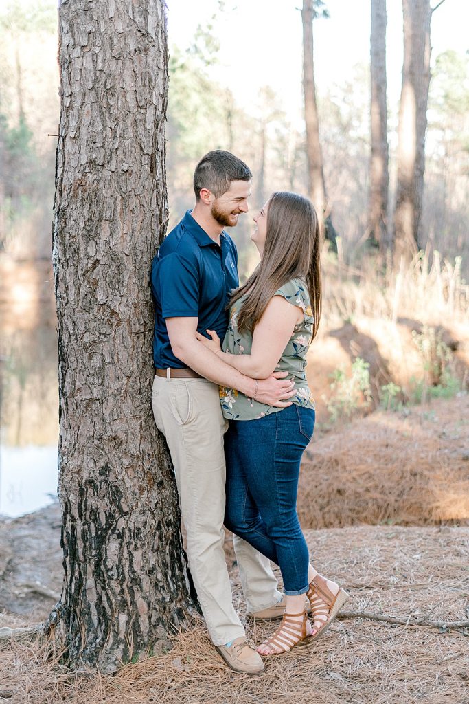 Couple leaning against tree smiling at each other