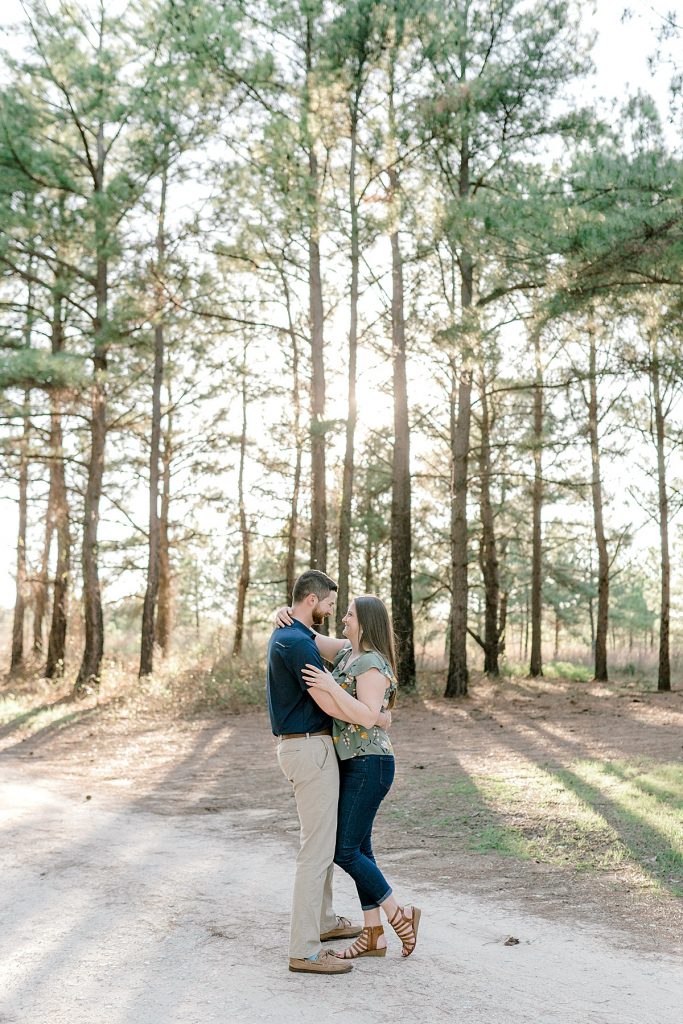 Couple embracing woods in sunlight at Wildcatter Ranch 
