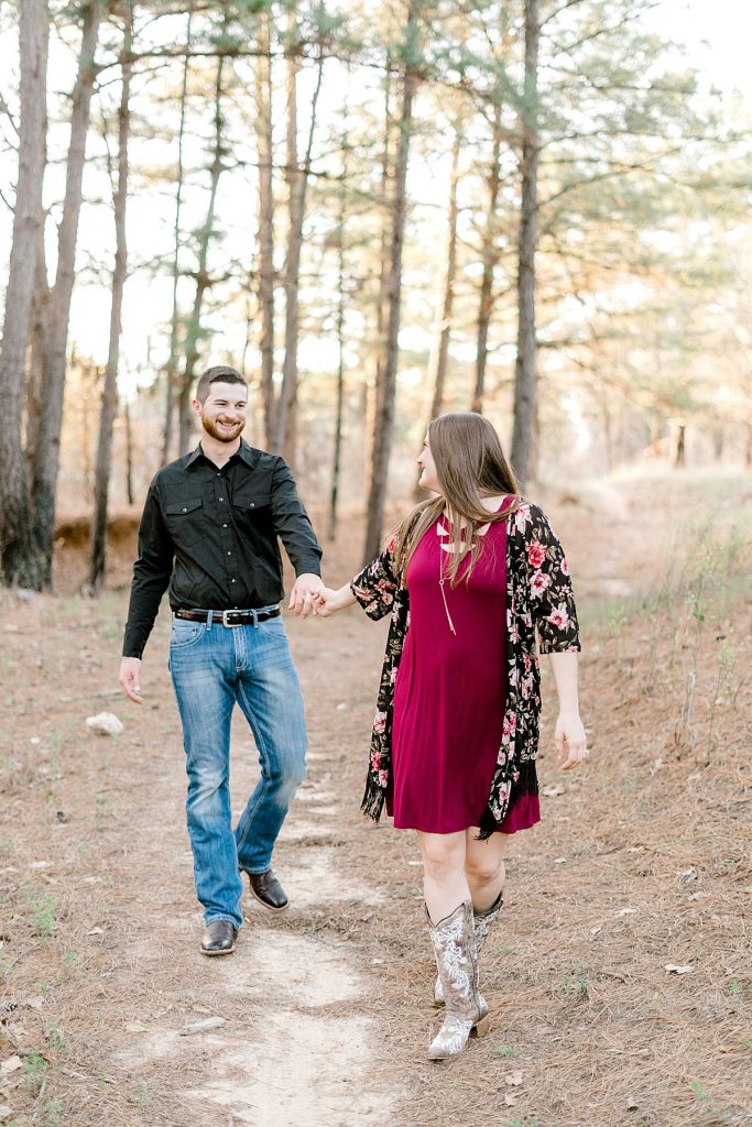 Engaged couple walking through woods at Wildcatter Ranch 