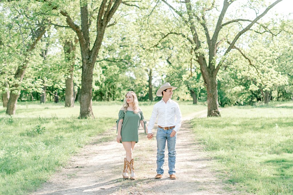 country guy and girl holding hands in middle of dirt road