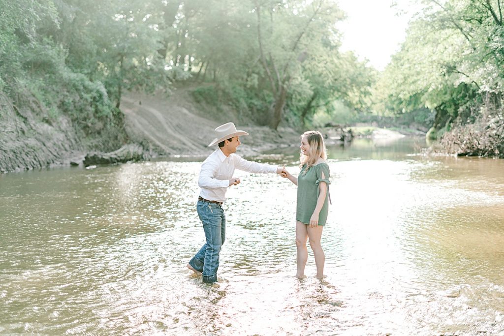 Couple walking and playing in creek bed during Five Oaks Farm engagement session 