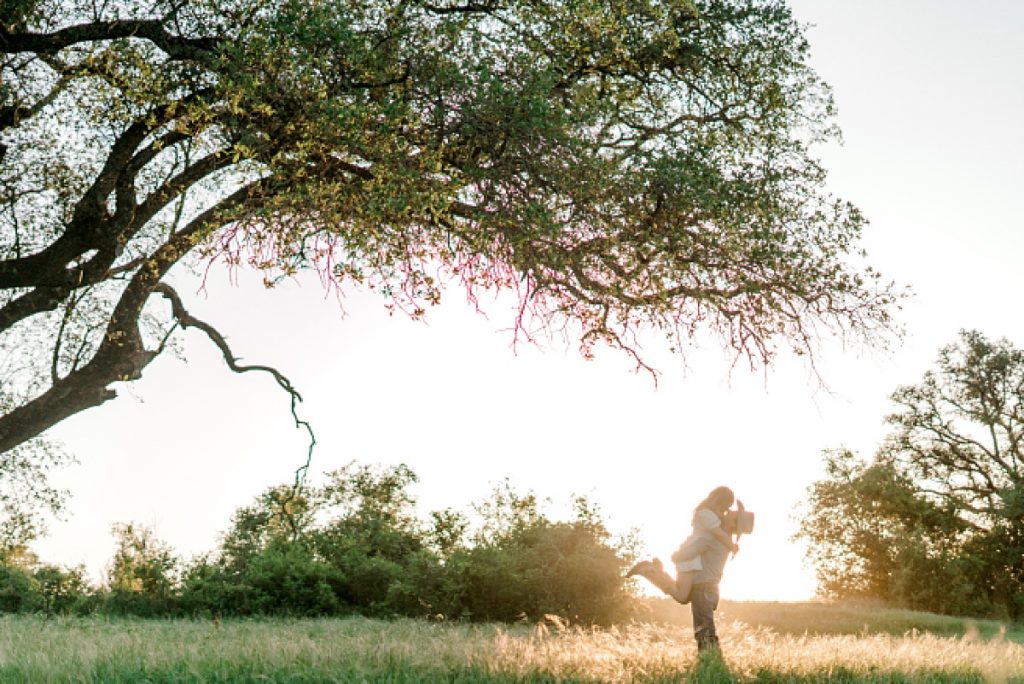 Guy lifts up girl and kisses her under large tree at golden hour | Hamilton/Hico Engagement 