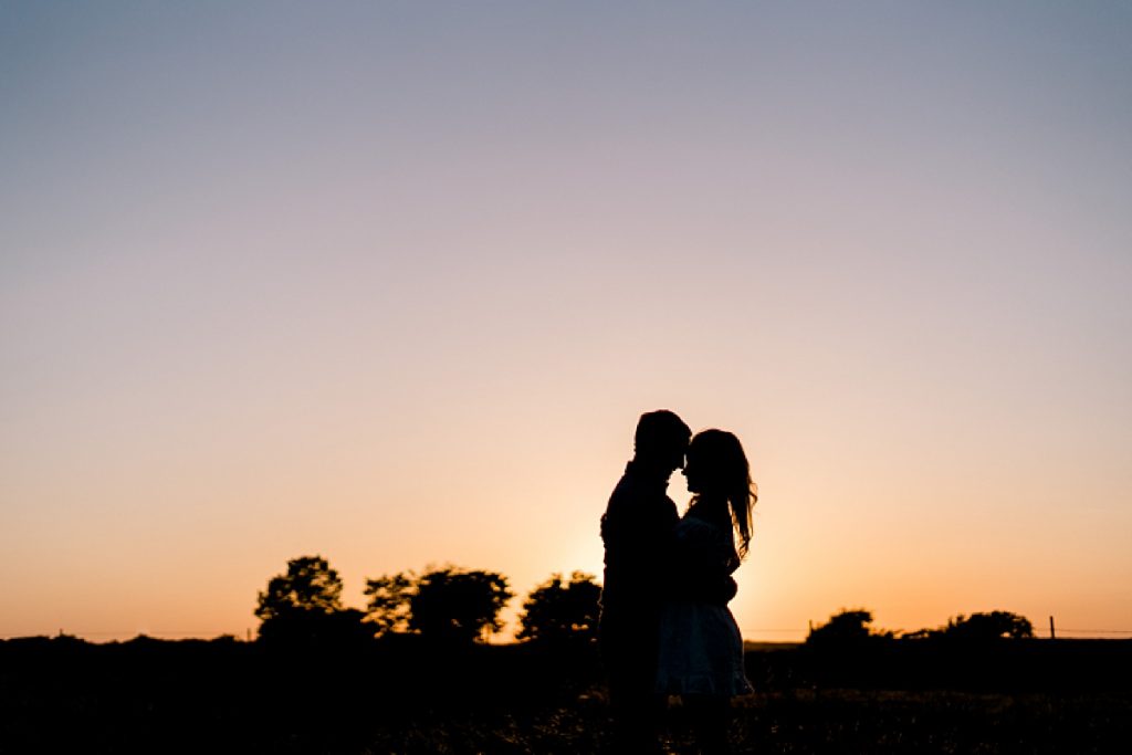 Couple nuzzling silhouette at sunset at their Hico Ranch