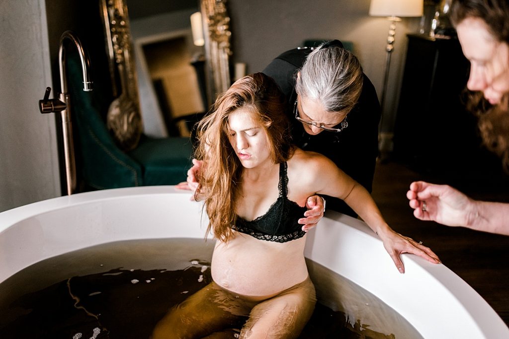Doula helping mom into special healing bath after giving birth| Origins Birth & Wellness Collective| origins natural birth