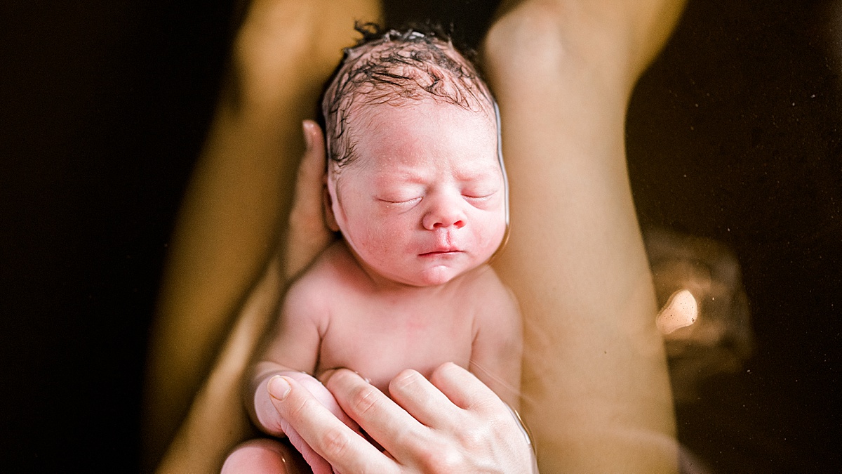 newborn being held in bath