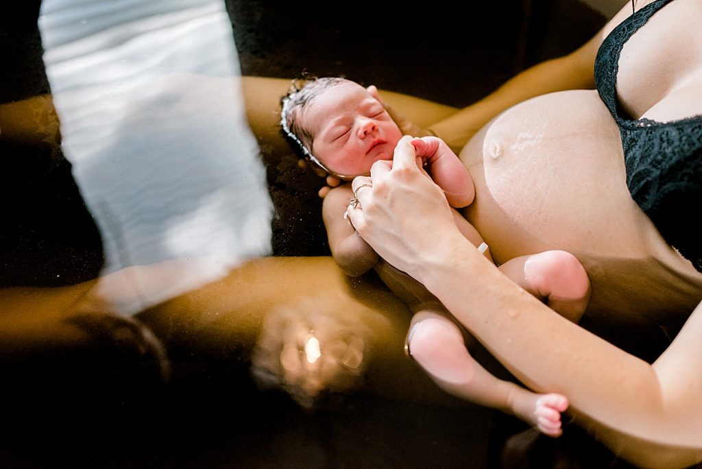newborn Luke held by mom in bath at Origins Birth Center 