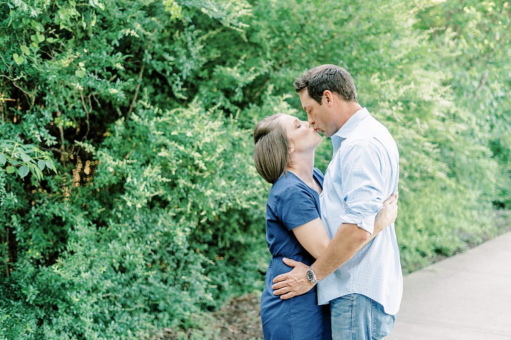 Couple kissing next to bushes