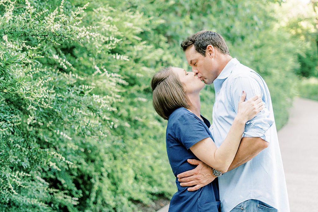 Couple kissing next to bushes