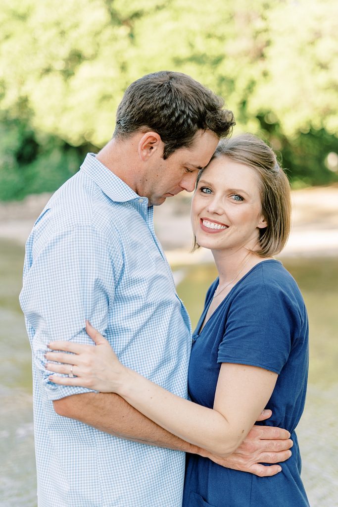 Guy and girl embrace while girl smiles into camera at their Airfield Falls Engagement Session 