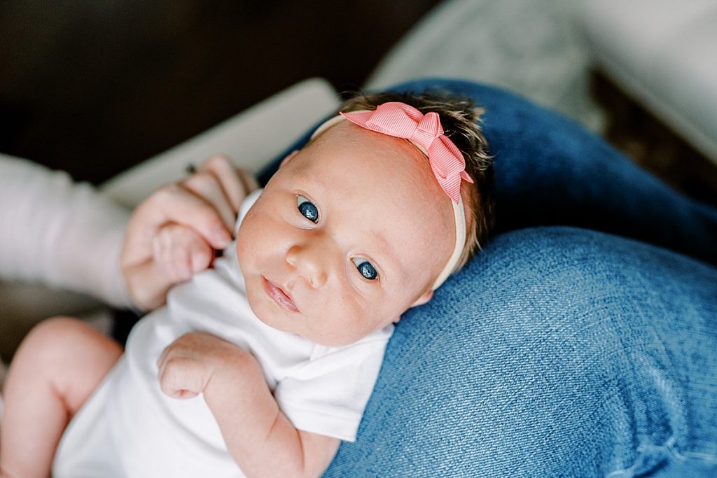 Baby in pink bow on moms lap| in Fort Worth Lifestyle Newborn Family Session