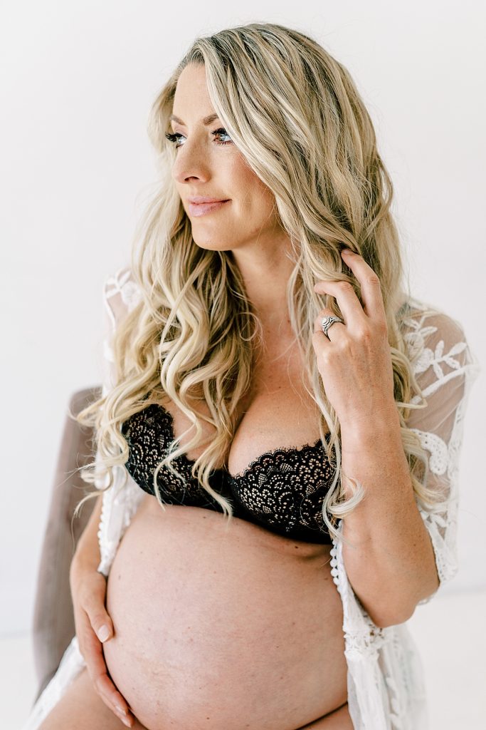 Pregnant woman in lingerie sitting touching her belly