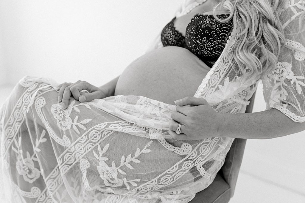 BW pregnant woman in lacy lingerie sitting in chair at the Lumen Room Fort Worth Maternity session