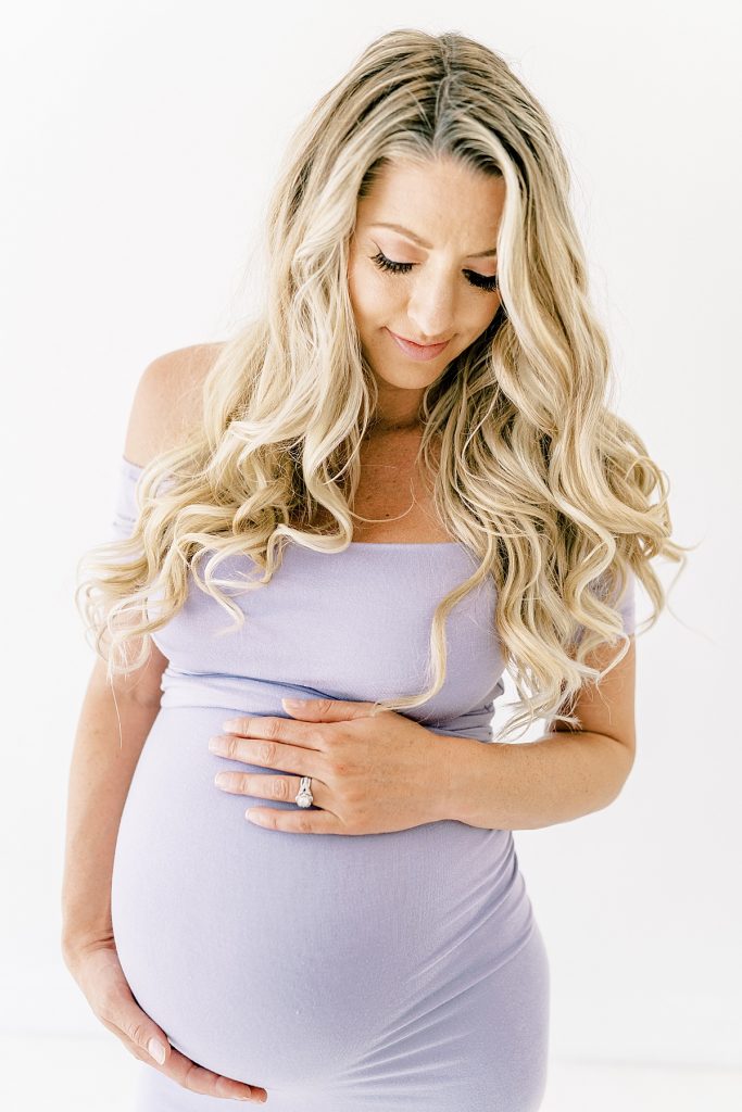 blonde woman looking down at pregnant belly