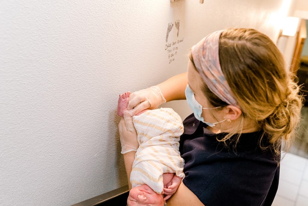 Nurse stamping newborn baby foot to wall at Fort Worth Birthing & Wellness Center