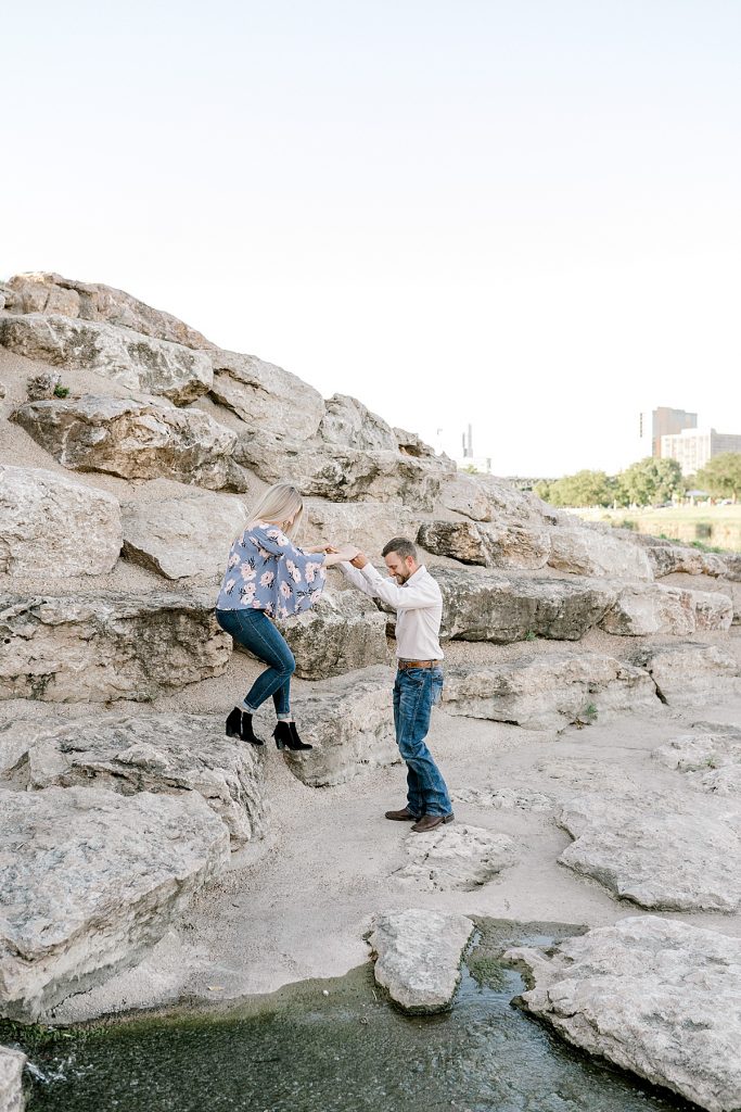 Guy helps girl down rocks in Trinity Park engagement session