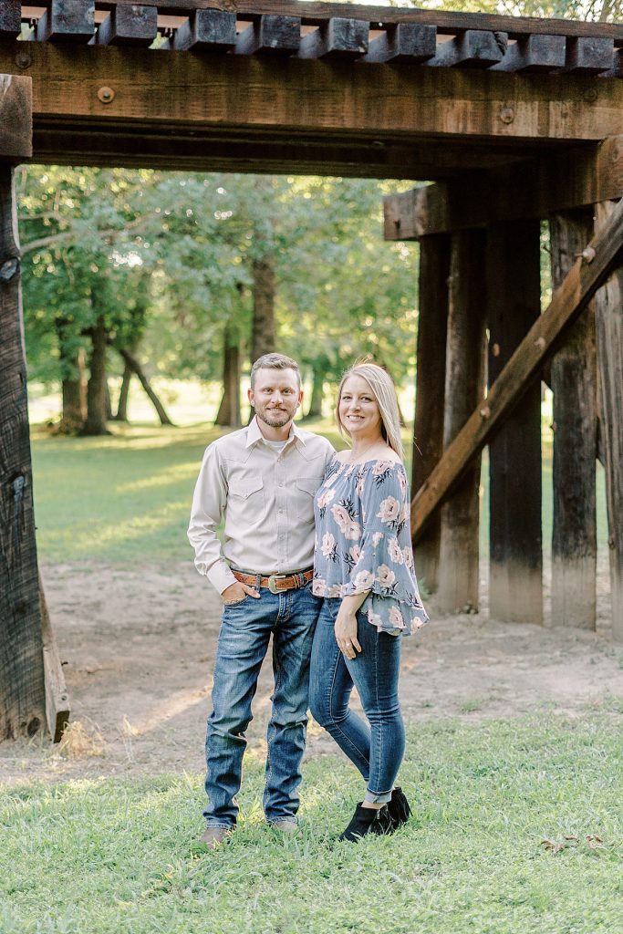 Couple standing under railroad at Fort Worth engagement