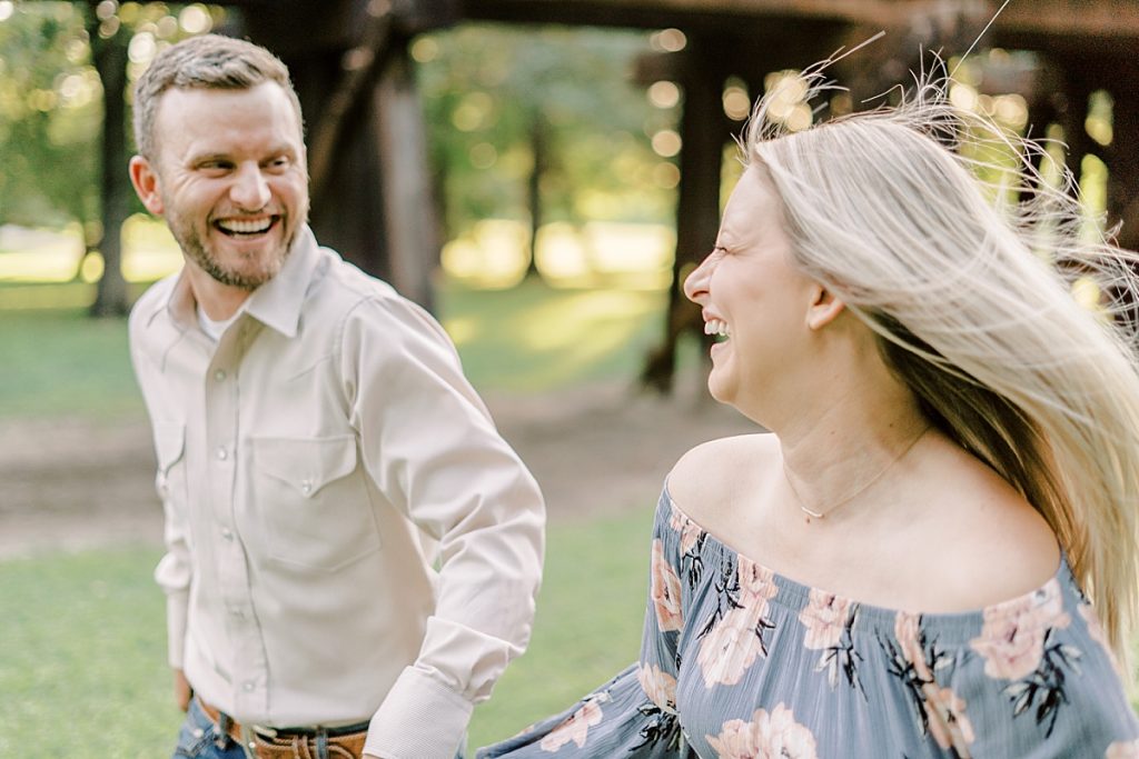 Engaged couple running through field in Fort Worth stockyard engagement