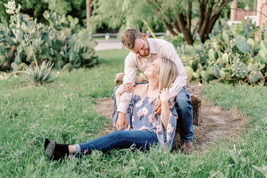 Couple cuddling on rock in cacti field Fort Worth engagement