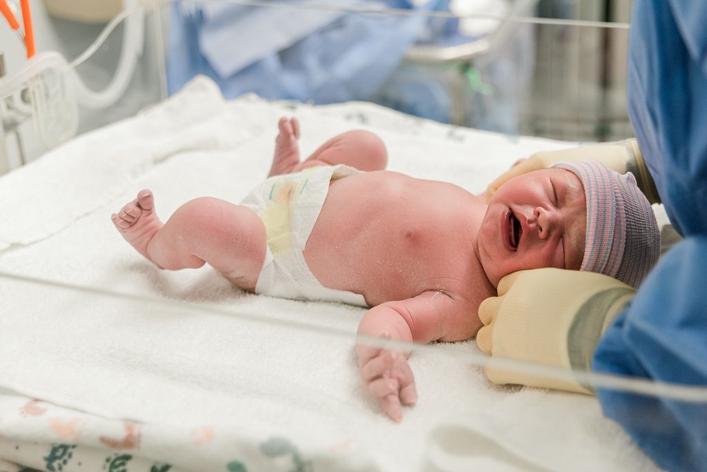 Newborn baby in bassinett measured after delivery