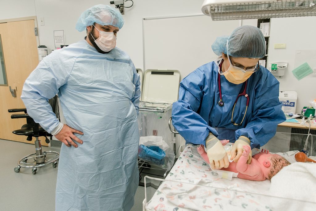Father watches as nurse puts diaper on newborn