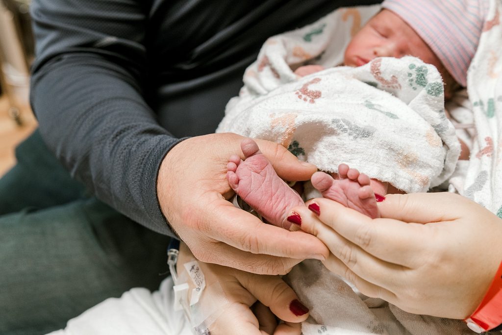 Parents holding newborn baby feet